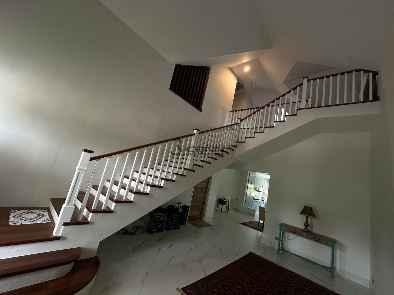 A long white-baluster staircase railing with a Nyatoh timber handrail sweeping through a double-height hall.