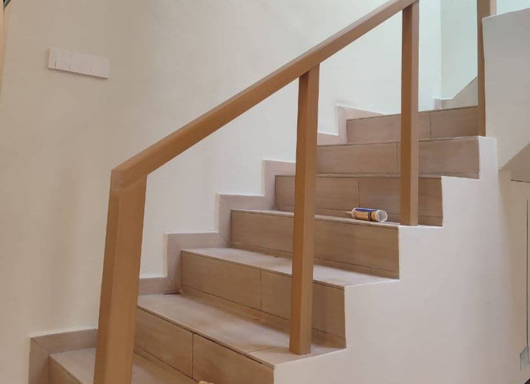 A light-oak timber handrail and newel post on a tiled flight of stairs.